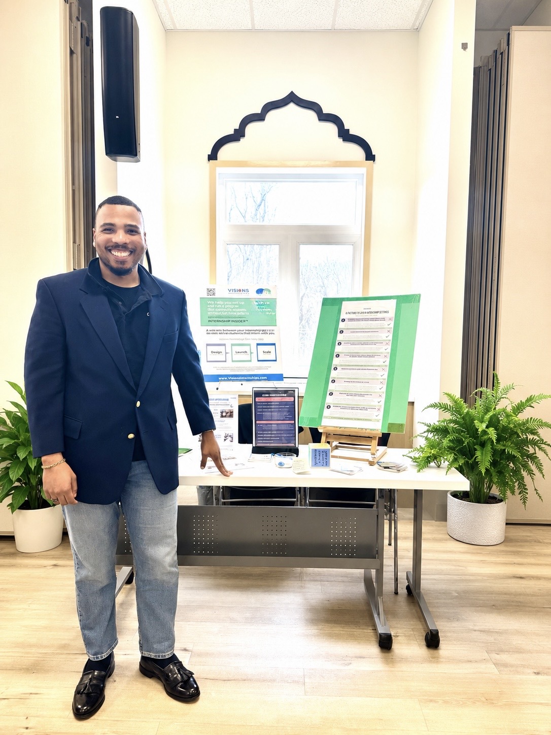 Bryon Lewis-Cummings standing beside conference program materials
