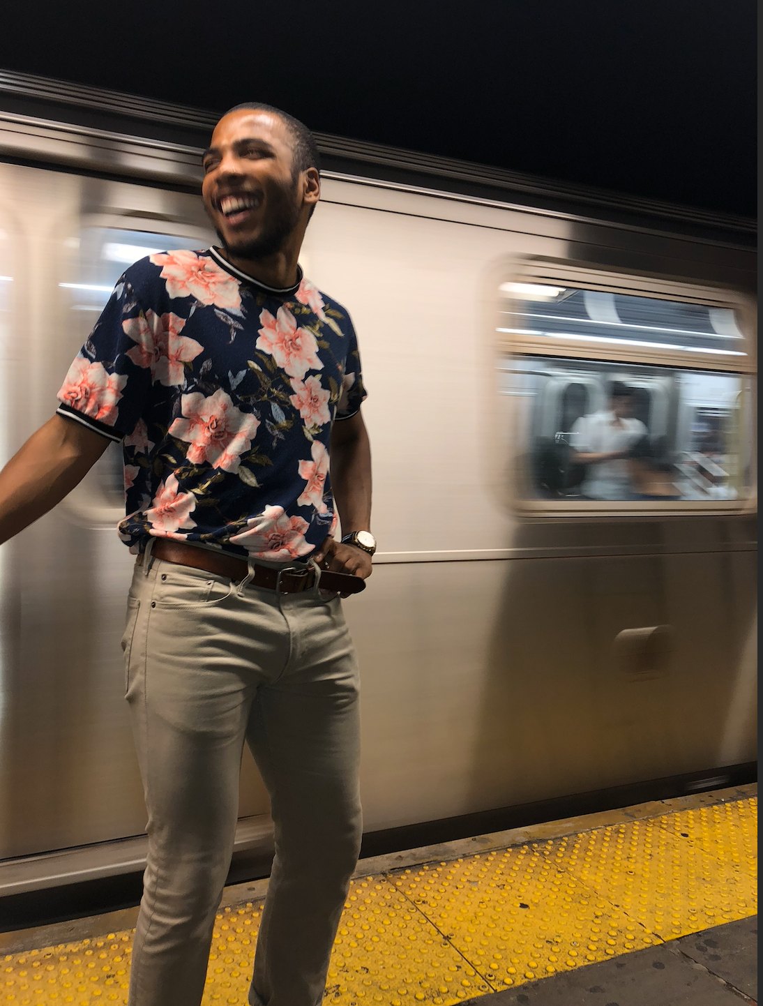 Bryon smiling by a moving subway train